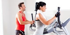 Man and woman with elliptical cross trainer at gym