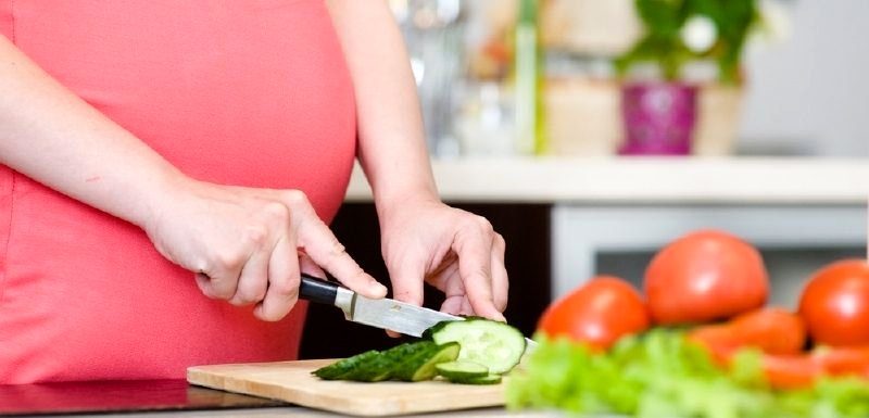 Беременная женщина делает салат